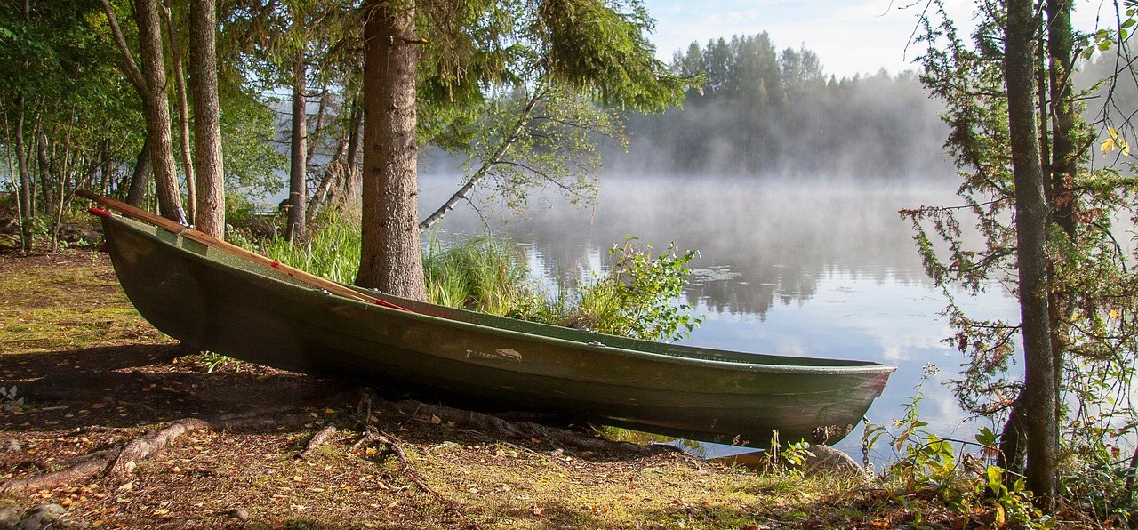 Soutuvene, joka on vedetty rannalle. Taustalla mäntymetsää. Järven päällä on usvaa.