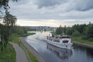 Sisävesilaiva salmessa kesäisessä maisemassa.